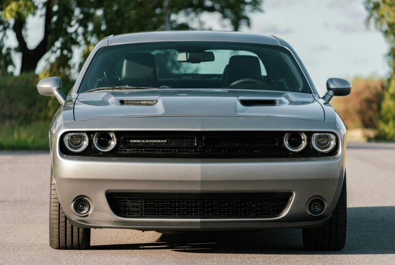 the front end of a silver car parked on a road