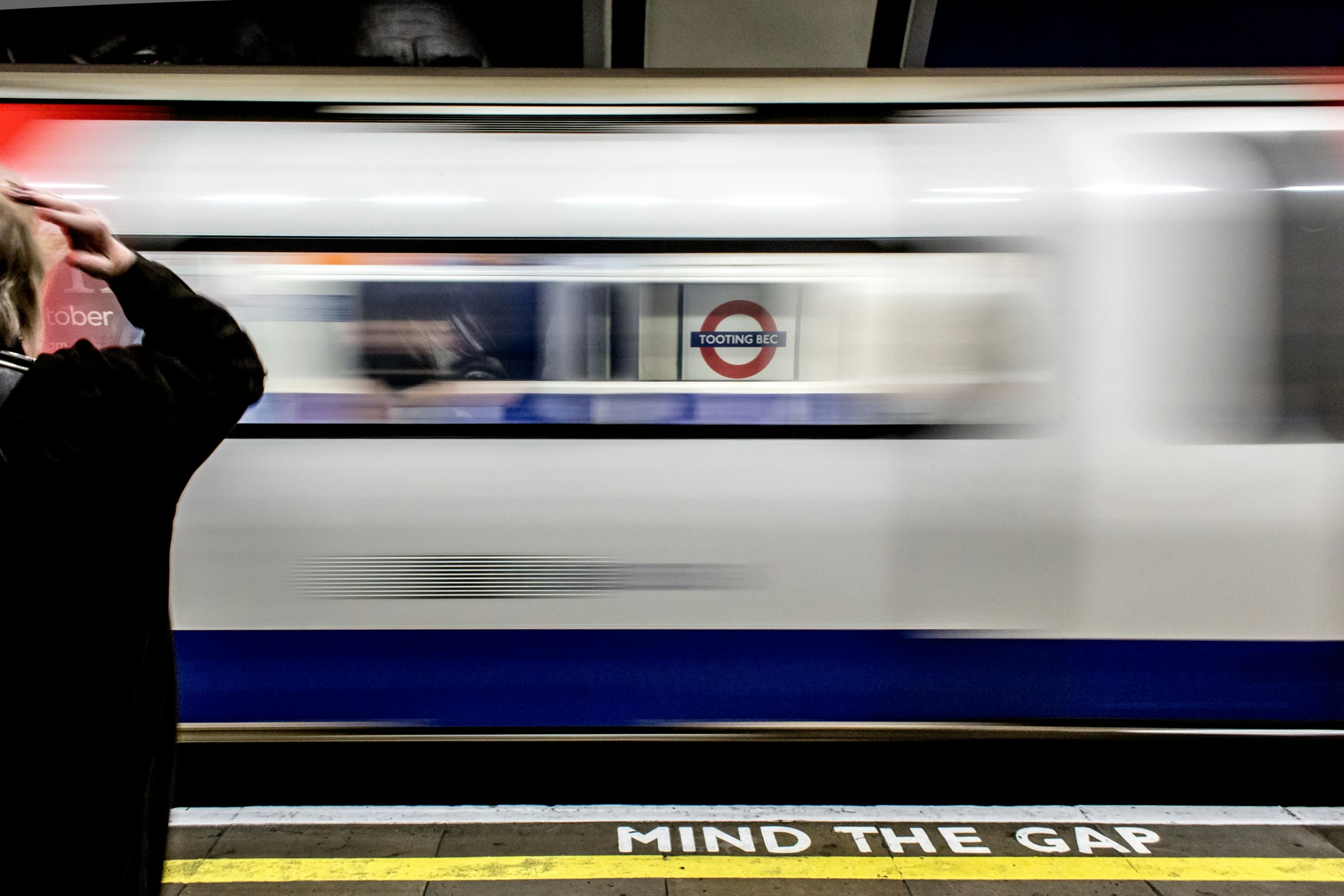 person taking a picture at train station as train approaches