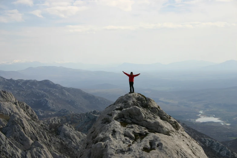 a man standing on top of a mountain on top of a stone