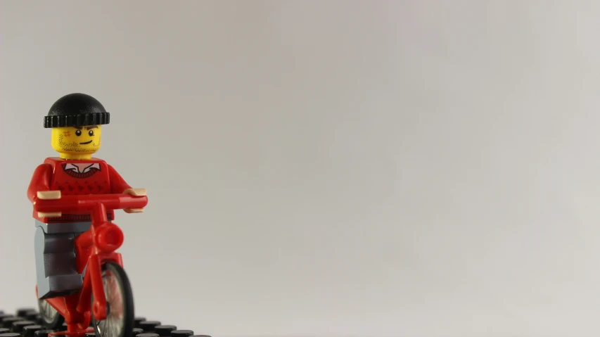 a lego person wearing a red shirt and black hat with a bicycle