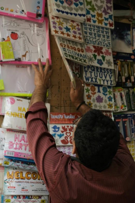 a man working on stickers hanging from a wall