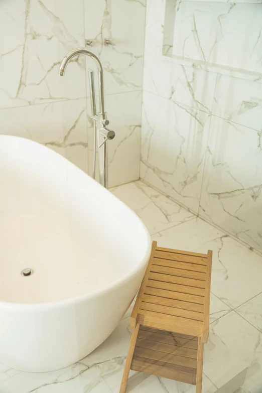 a small wooden chair sitting in front of a bathtub