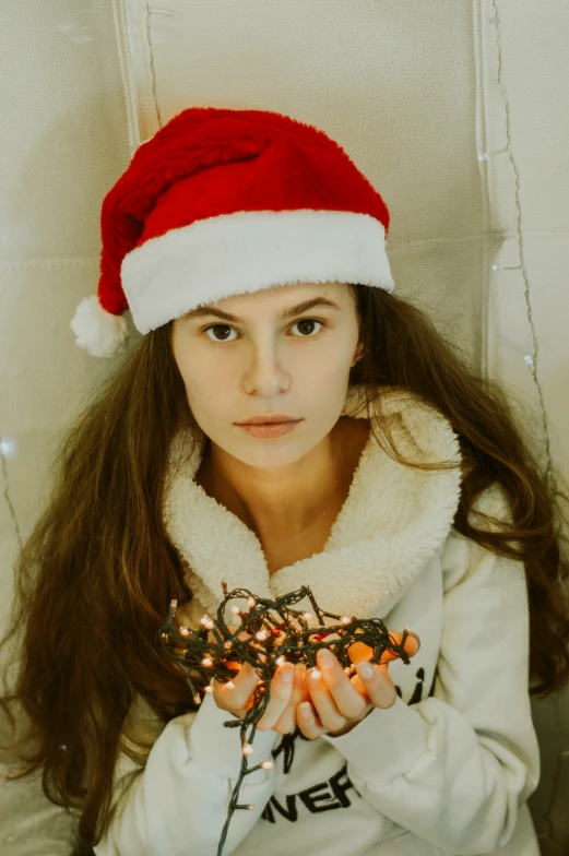 a pretty  in a christmas hat holding christmas lights