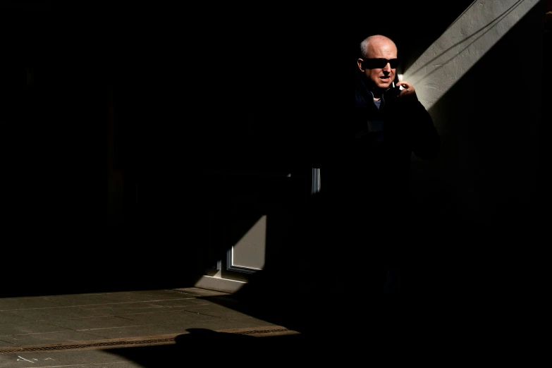 an older man talking on a phone standing in the dark