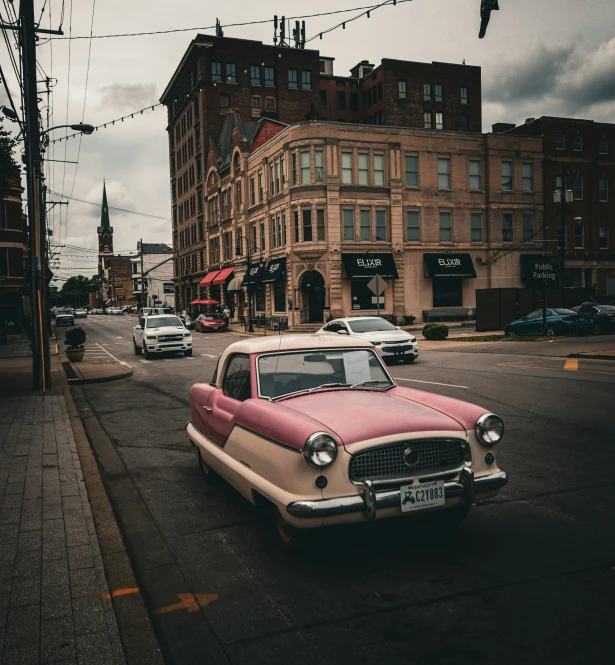 a classic car in the middle of the road in an old fashion neighborhood