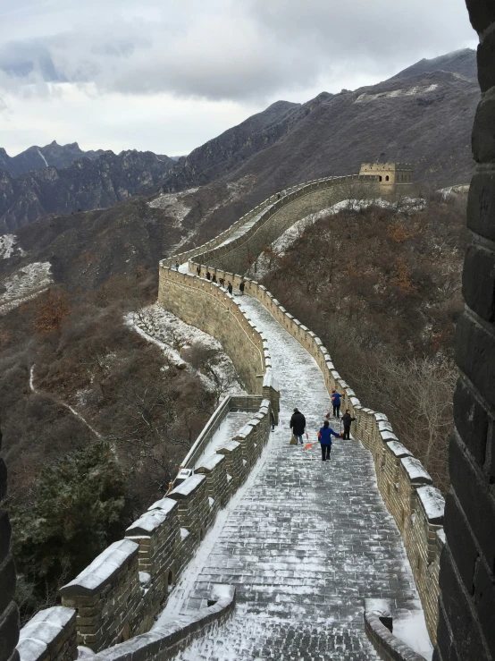 a person stands on a narrow snow - covered section of the great wall