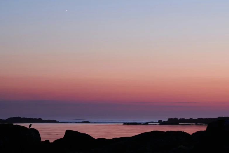 people walking on a beach as the sun rises