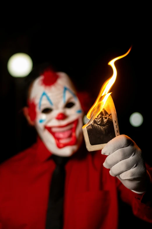a clown is showing off a burning card
