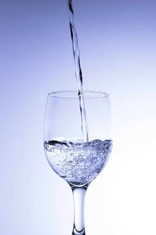 a glass of water with some liquid pouring in it