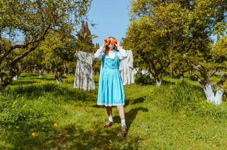 woman dressed in blue dress walking through an apple orchard