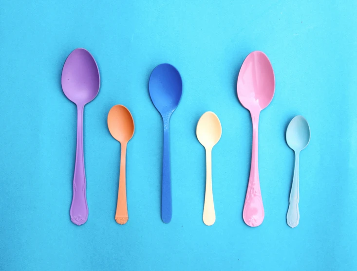 six plastic spoons with colored tips lined up in a row