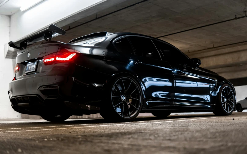 black car on a parking garage floor next to a wall