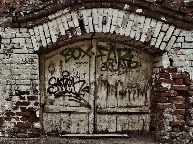 a close up of a brick wall with a door with graffiti on it