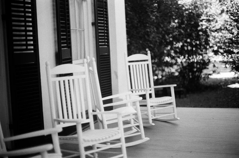 the rocking chairs are sitting outside of the house