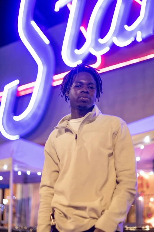 a young man standing next to a neon sign