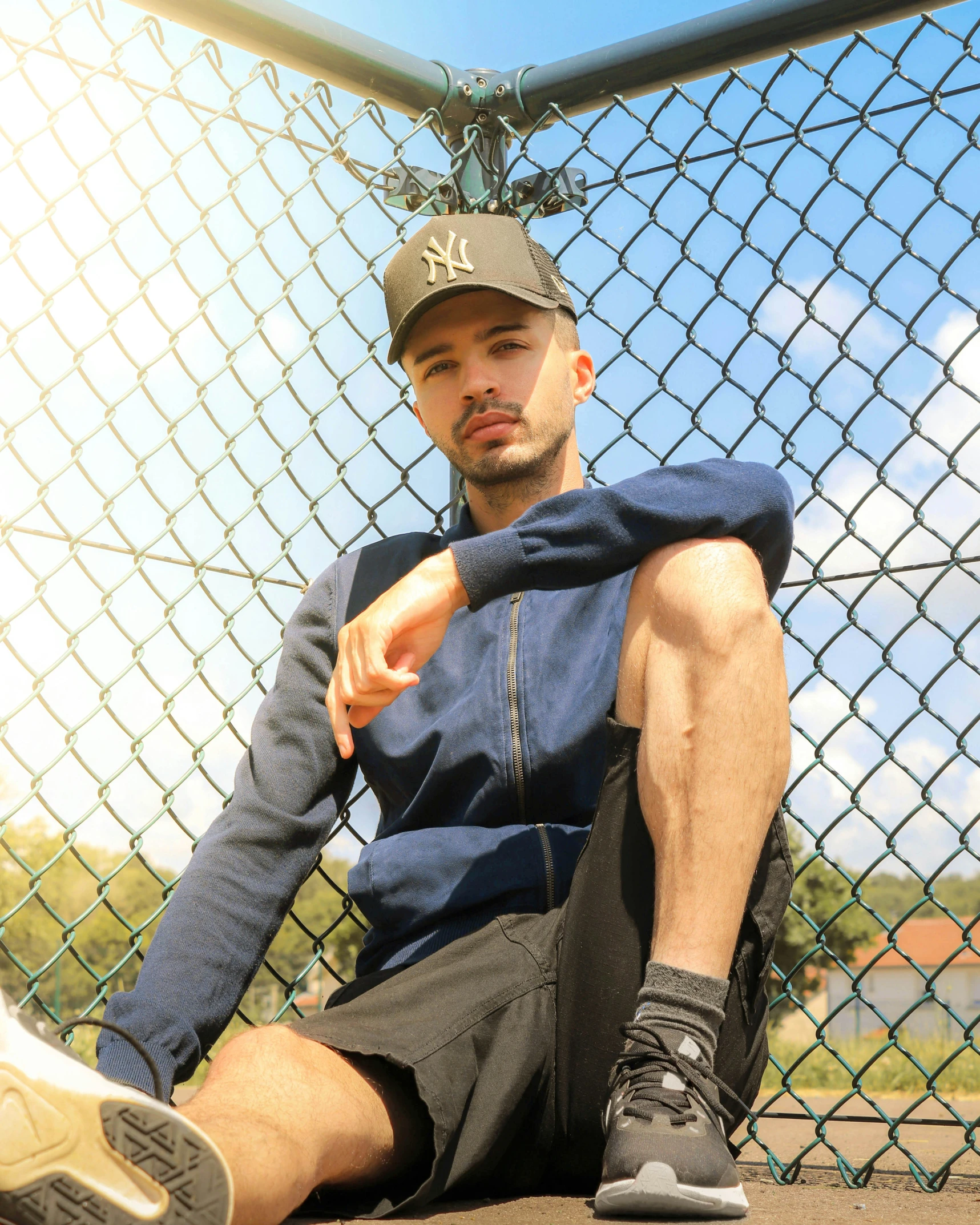 a man sitting against a fence with his feet on the ground