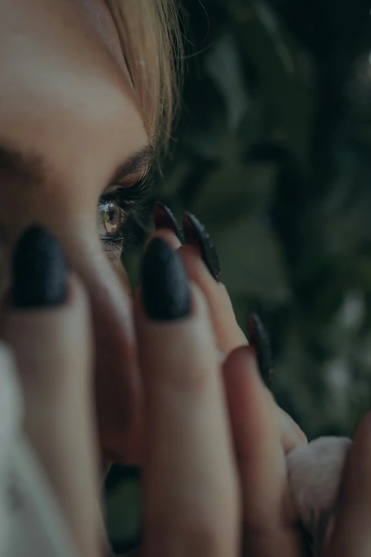 closeup of an eye from the left, with the reflection of a woman's eyes and her hand on her thumb