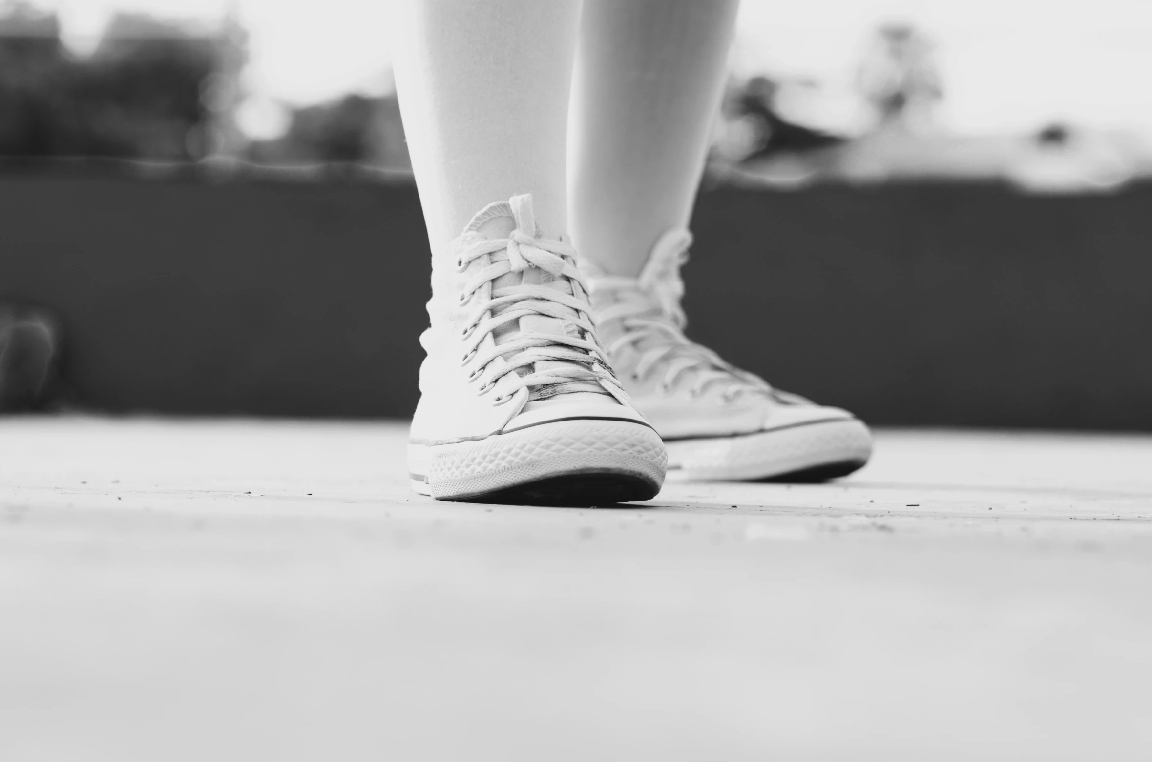 a black and white po of someones legs with tennis shoes