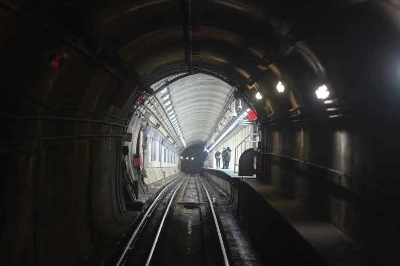 a long train traveling through a tunnel next to train tracks