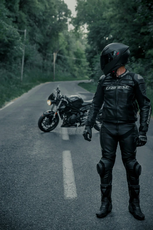 a man is wearing black and standing next to a motorcycle