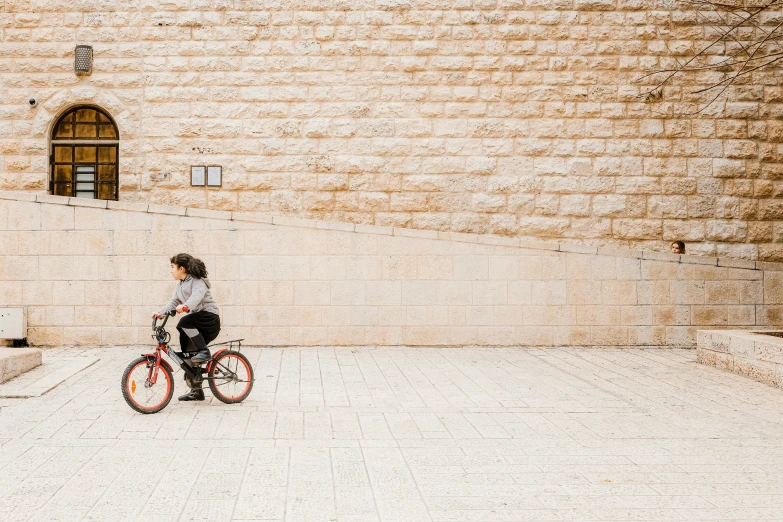 a man on a red bicycle next to a wall