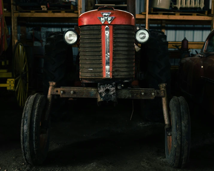 an old red tractor being worked on in a workshop