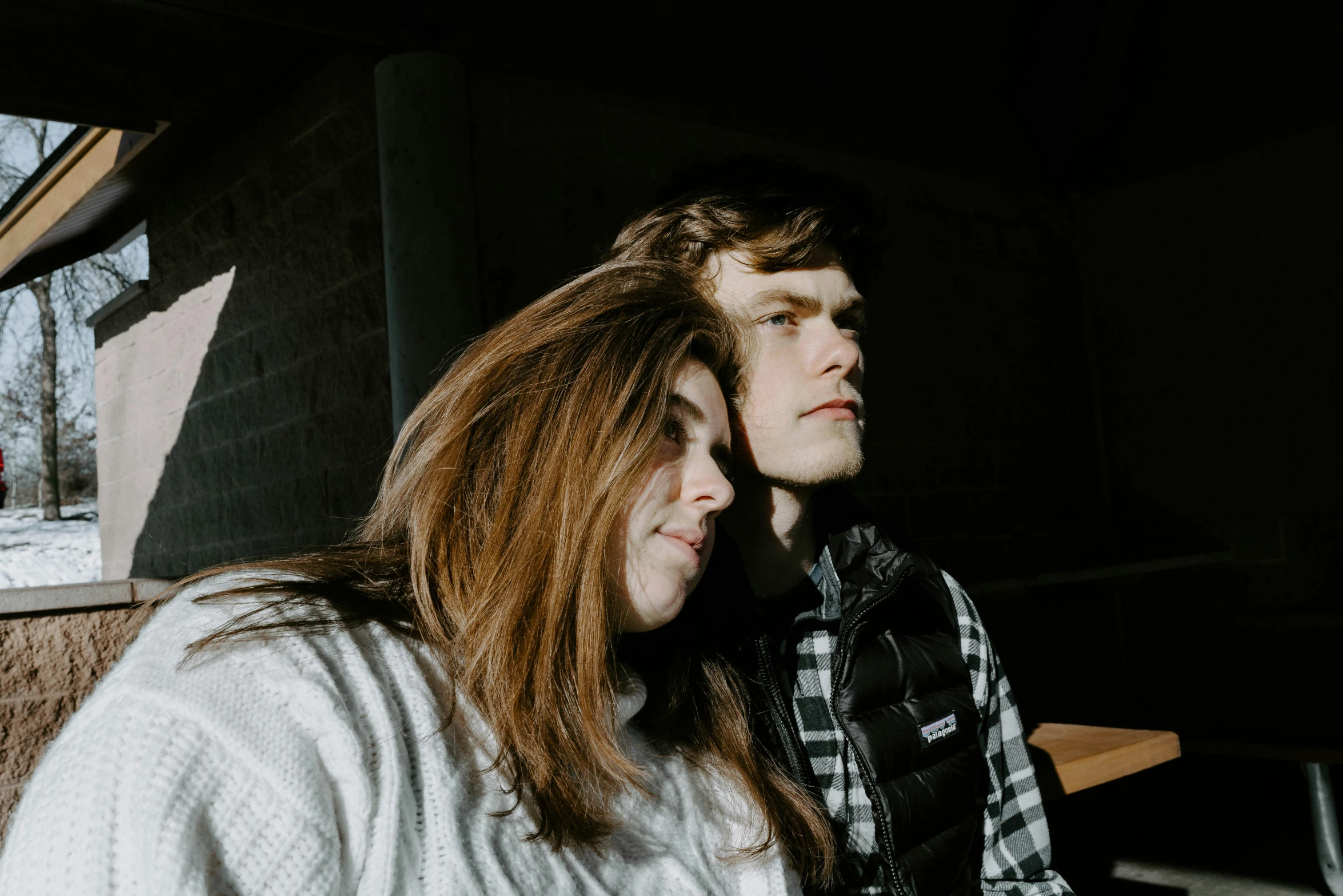 two people sitting at a table, looking off in the distance