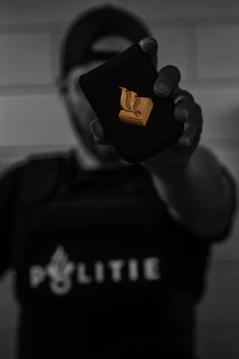 a person holding a little black bag with a gold logo