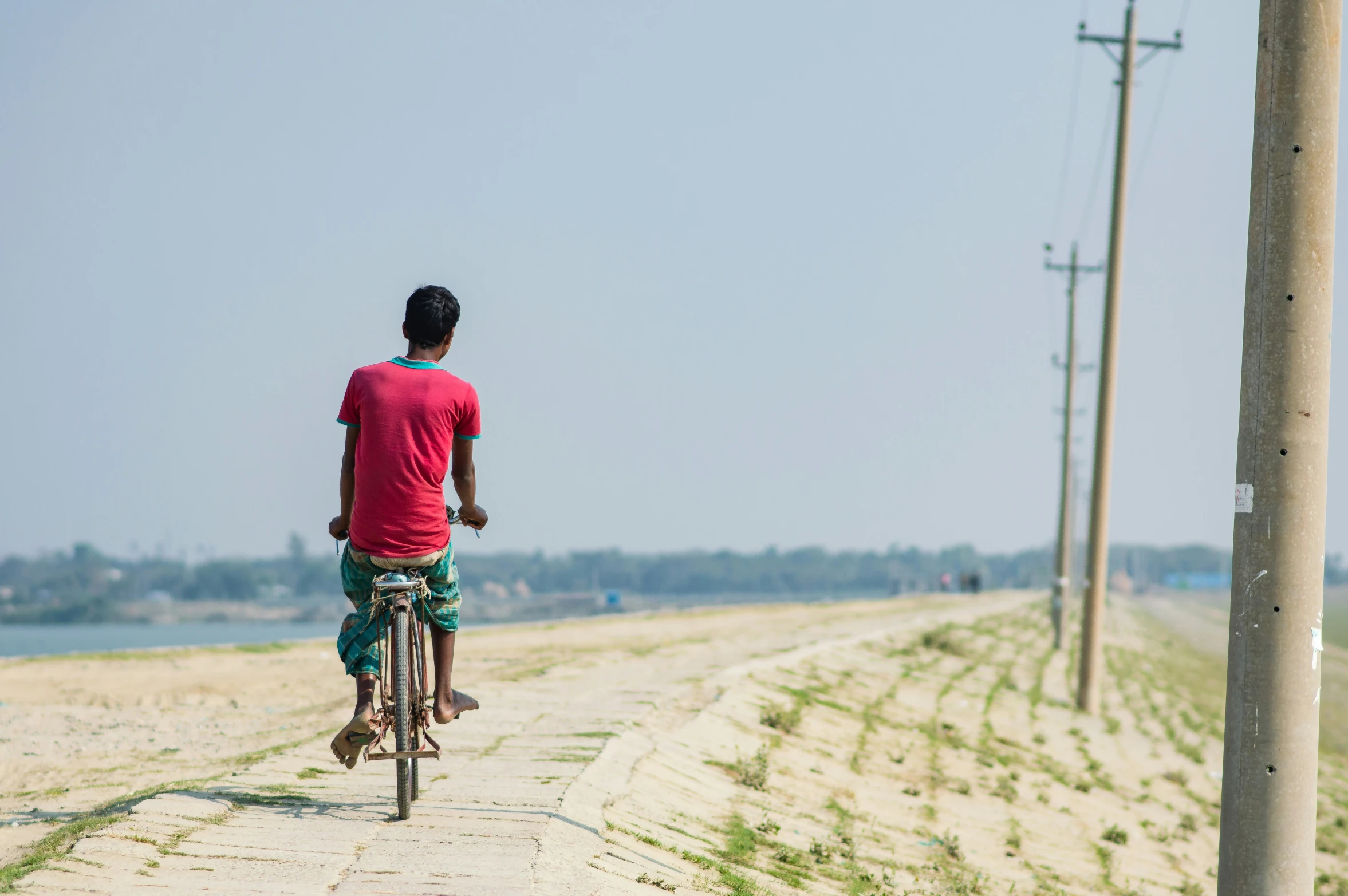 a boy riding his bike down the side walk