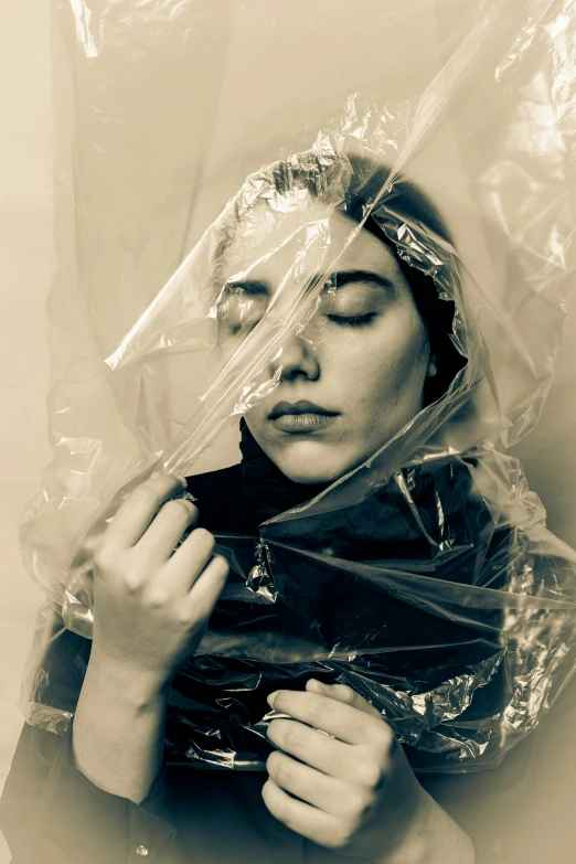 a woman with her eyes closed wrapped up in plastic