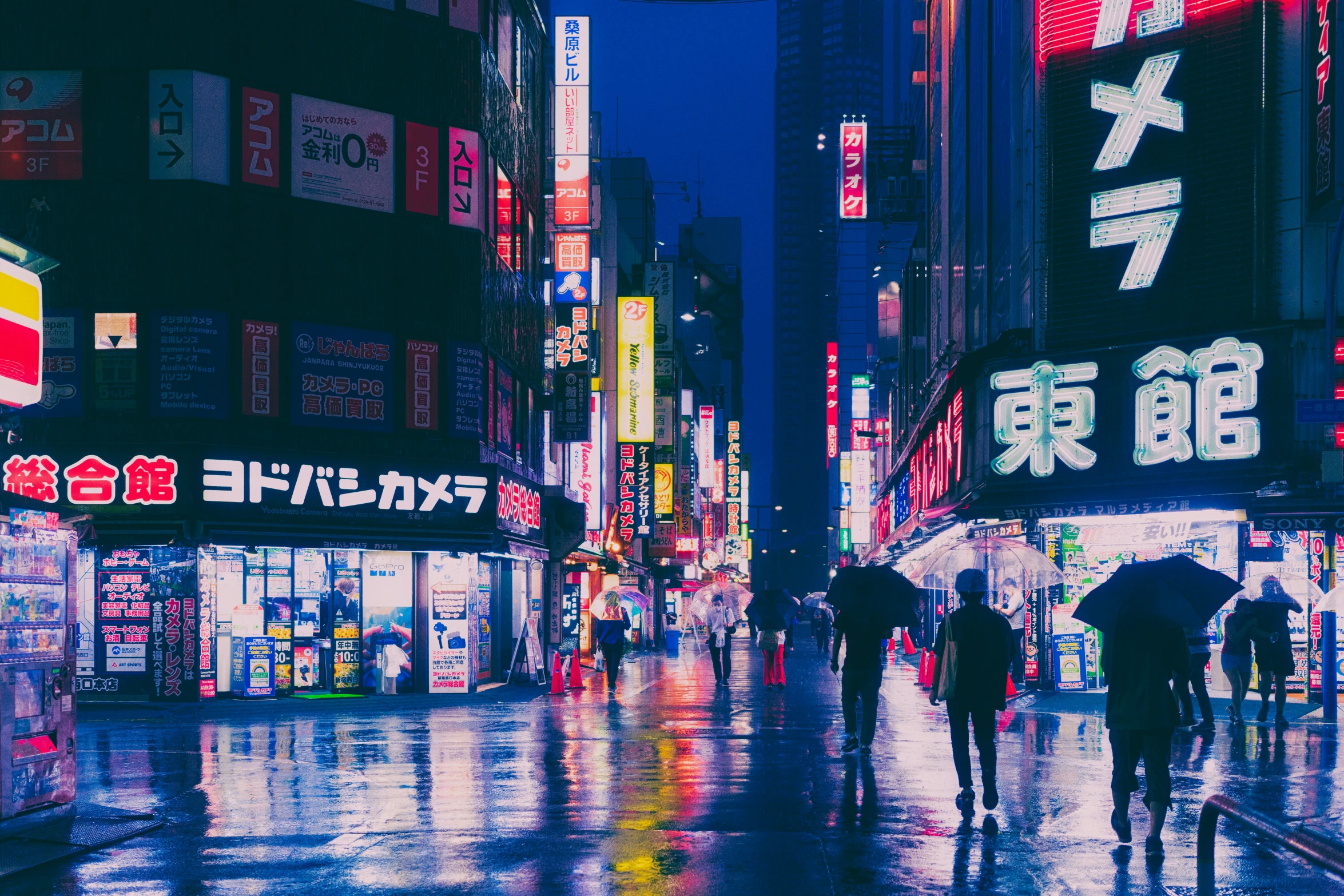 people with umbrellas are walking down a dark city street
