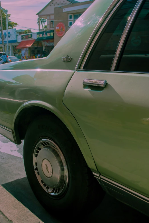 a green car parked at a curb in the street