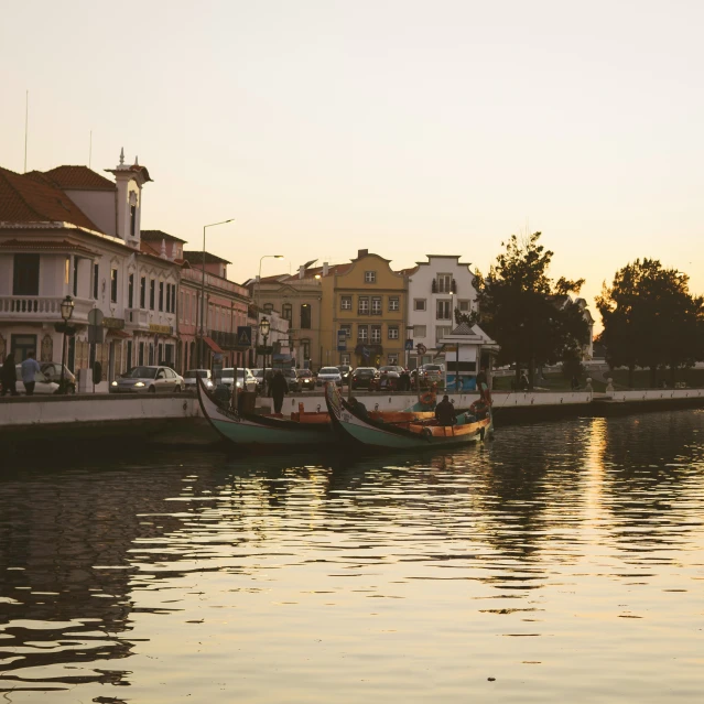 a couple of boats sit in the water in front of some buildings