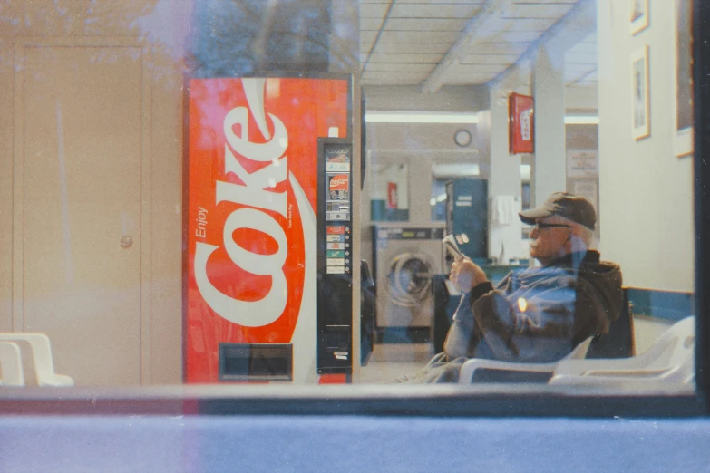 a man sits on a bus with a can of coke in his hand