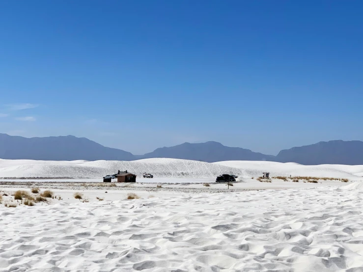 a group of small shack on the beach with mountains in the background