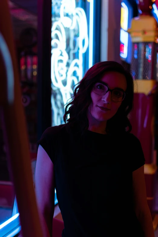 the woman in glasses is standing in front of neon signs