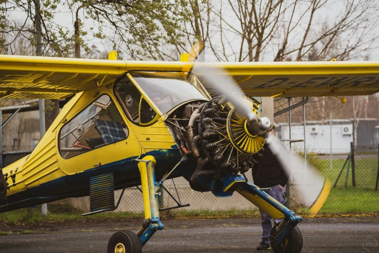 the man stands beside the small yellow plane