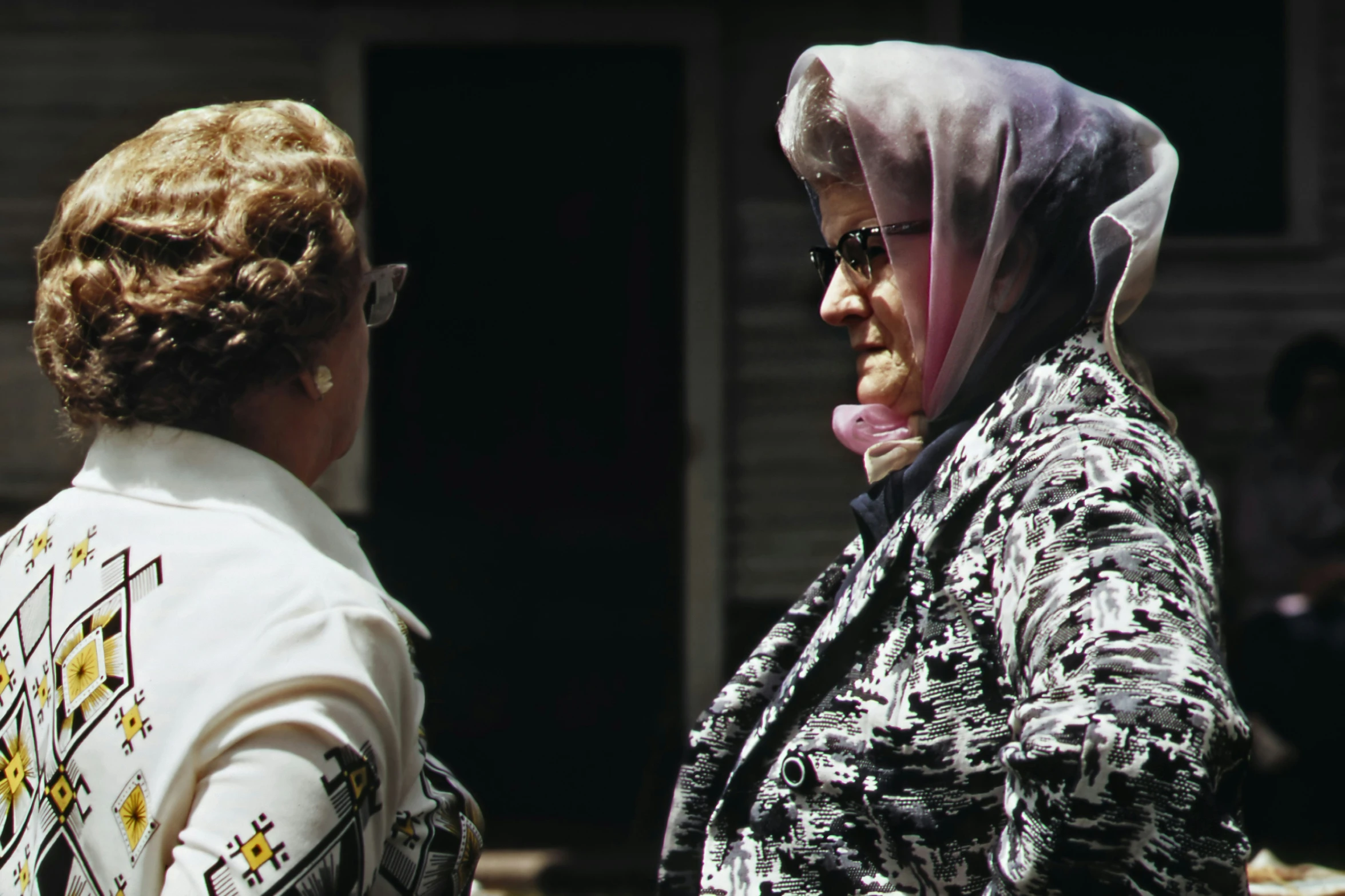 two women one wearing a scarf and the other holding a drink