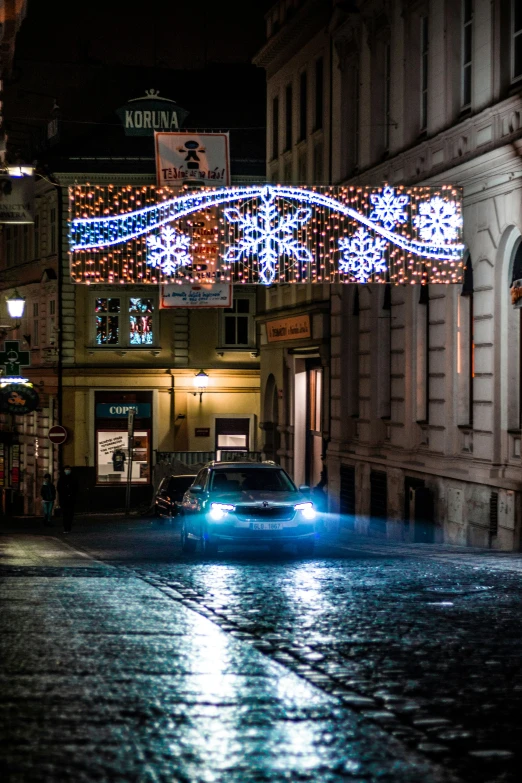 a car is driving through the city streets with christmas lights