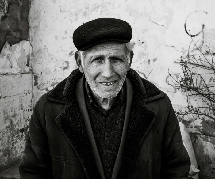 an elderly man in black coat and hat outside