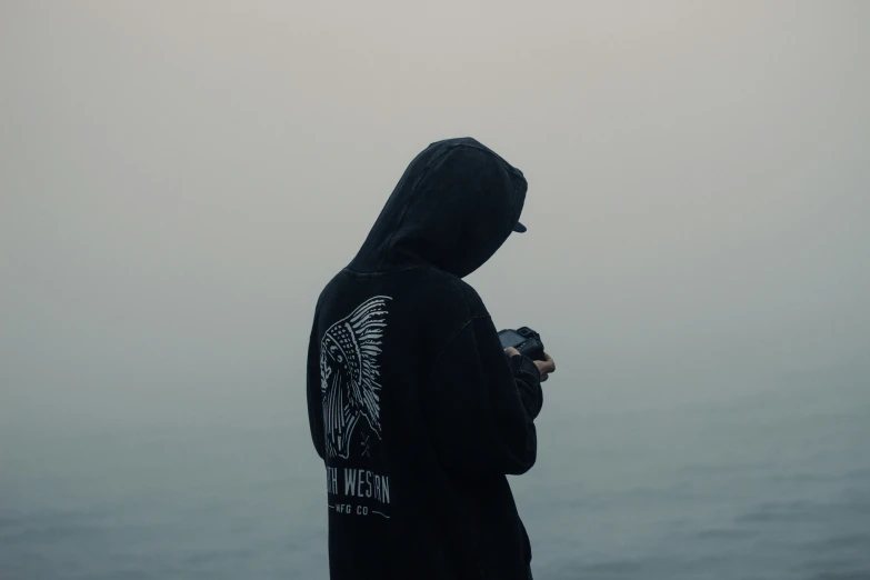 person in black sweatshirt standing by the water