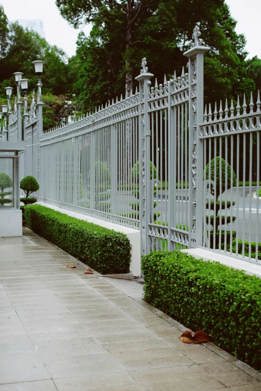 the white wrought iron gates of this building overlooks the trees