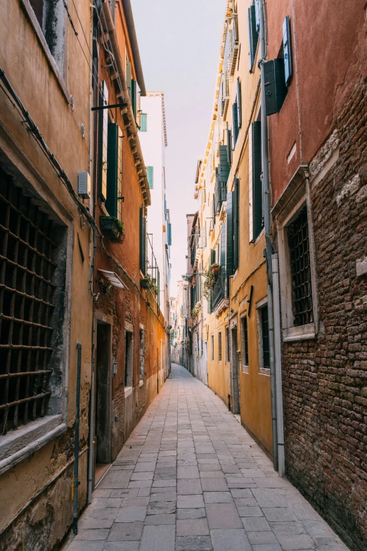 a long narrow alley between two buildings that have shuttered off windows on each side