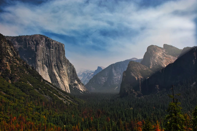 the sun is setting over mountains with trees on both sides