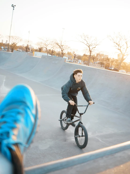 a person rides a bicycle near an empty skate park