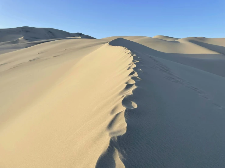 a landscape of sand dunes with footprints on them