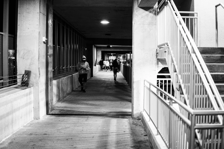 two people walking on either side of the building in a hallway