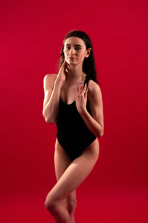 a woman in a bodysuit posing with her hands on her face