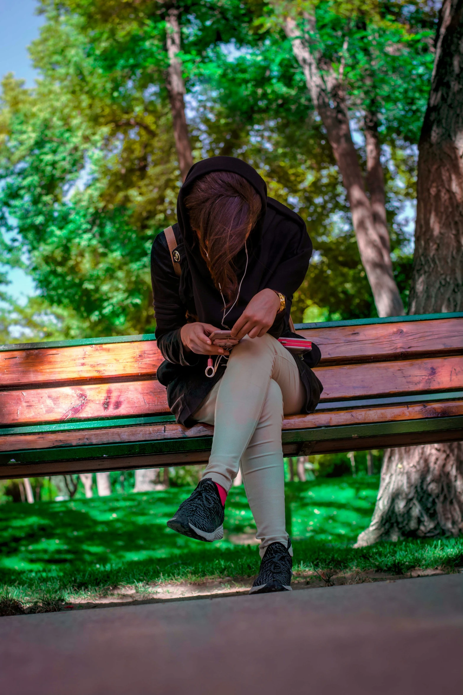 a young person is sitting on a wooden bench