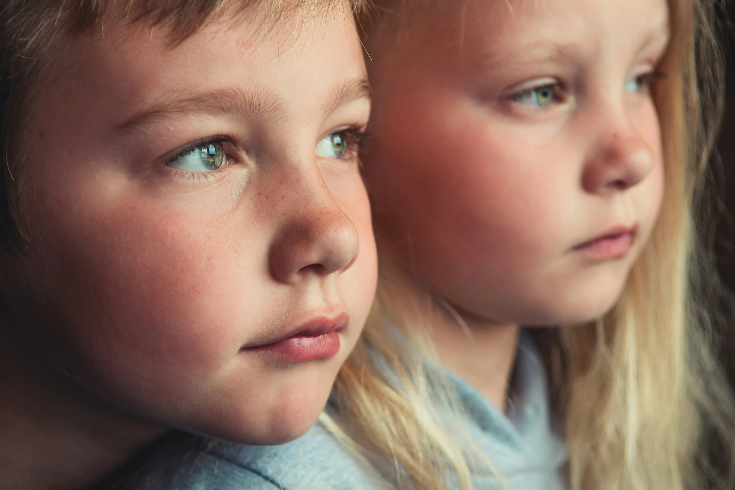 two children are looking out the window of their home